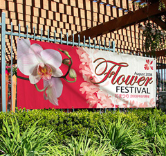 A vinyl banner hung on a fence announcing an event