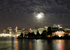 The moon peeks through the clouds over the Vancouver, British Columbia skyline
